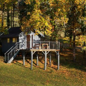 Cabane sur pilotis en Aquitaine, entourée de feuillage doré en automne.