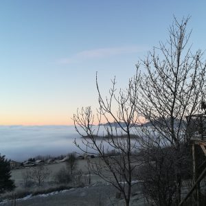 Cabane perchée en bois avec vue sur la mer de nuages au lever du soleil.
