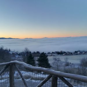 Hébergement insolite en bois avec vue sur les montagnes et la mer de nuages au lever du soleil.