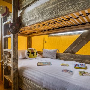 Cabane en bois colorée avec lits superposés et décor ludique pour enfants.