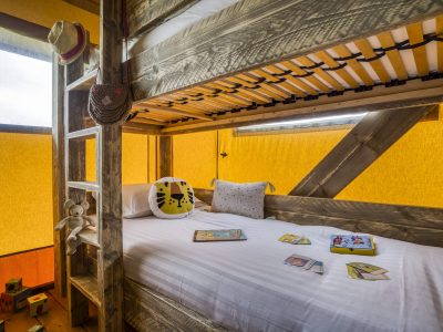 Cabane en bois colorée avec lits superposés et décor ludique pour enfants.