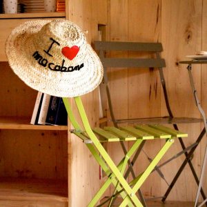 Cabanes en bois en Aquitaine, chapeau I love ma cabane sur une chaise verte.