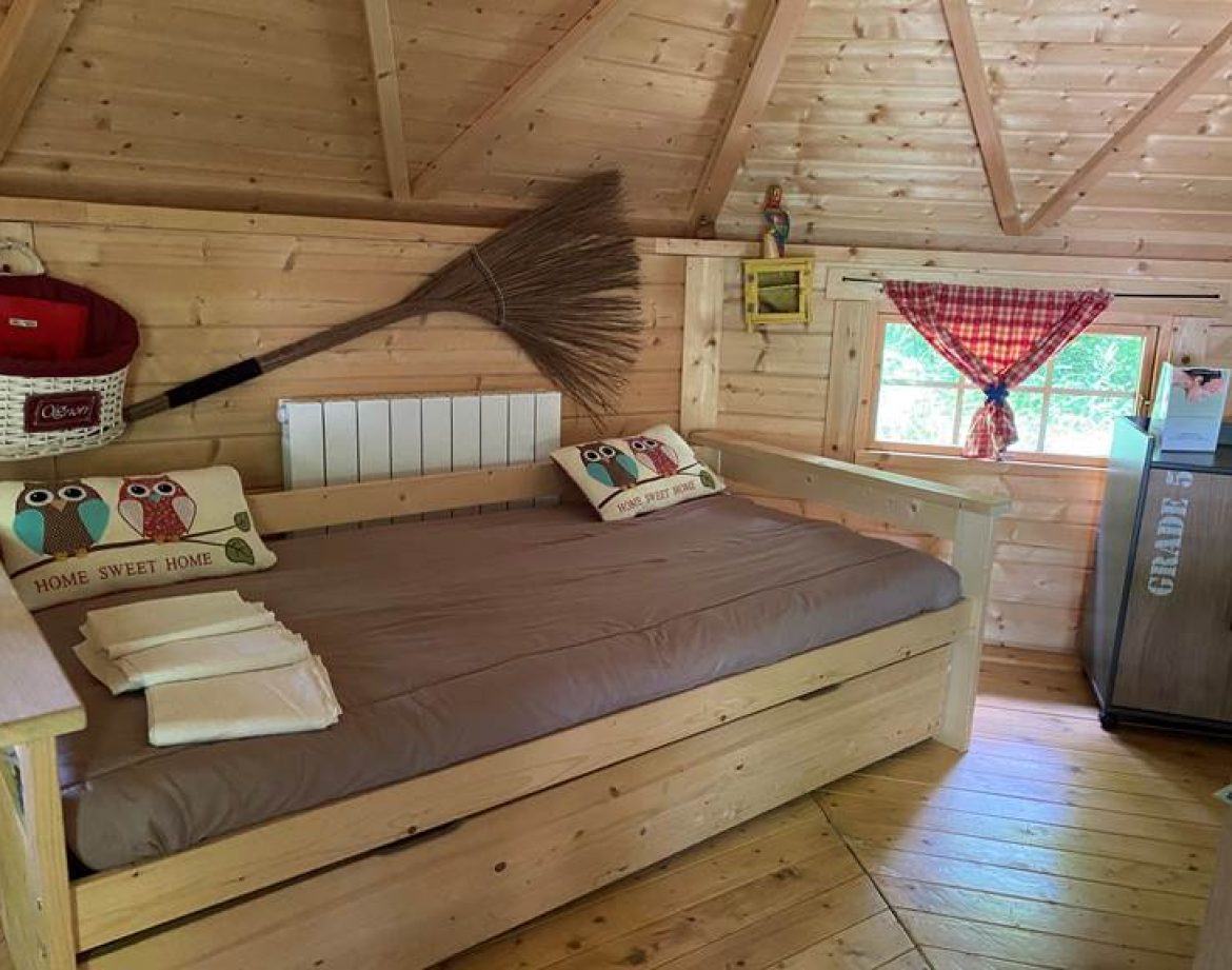 Cabane en bois avec un lit confortable et des coussins décoratifs de hiboux.