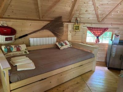 Cabane en bois avec un lit confortable et des coussins décoratifs de hiboux.