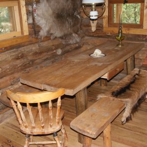 Cabane en bois chaleureuse avec table rustique et bancs en bois. Ambiance nature.