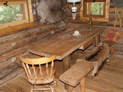Cabane en bois chaleureuse avec table rustique et bancs en bois. Ambiance nature.