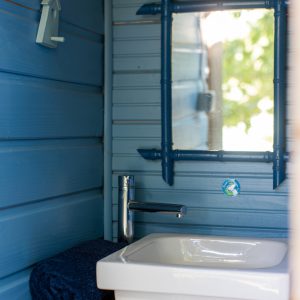 Salle de bain dun hébergement insolite en bois, murs bleus et lavabo moderne.