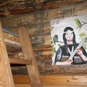 Cabane en bois avec une peinture colorée dune femme et des perroquets.