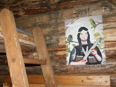Cabane en bois avec une peinture colorée dune femme et des perroquets.