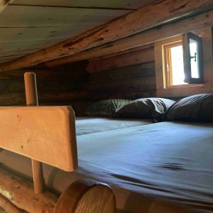 Cabane en bois dans les arbres, lit confortable sous un plafond en bois chaleureux.