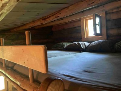 Cabane en bois dans les arbres, lit confortable sous un plafond en bois chaleureux.