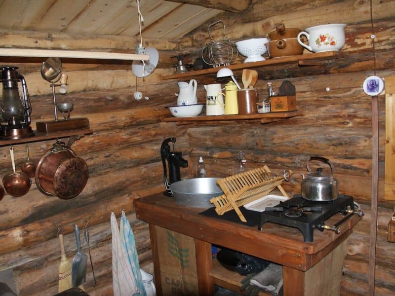 Cabane en bois avec une cuisine rustique et des ustensiles vintage.