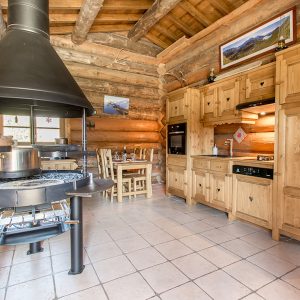 Chalet en bois chaleureux avec cuisine moderne et cheminée centrale.
