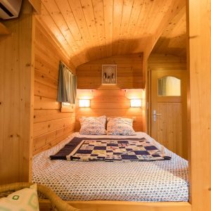 Cabane en bois chaleureuse avec lit douillet et murs en pin naturel.