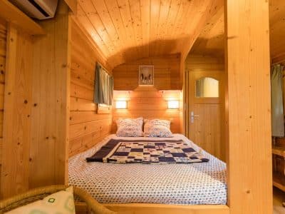 Cabane en bois chaleureuse avec lit douillet et murs en pin naturel.