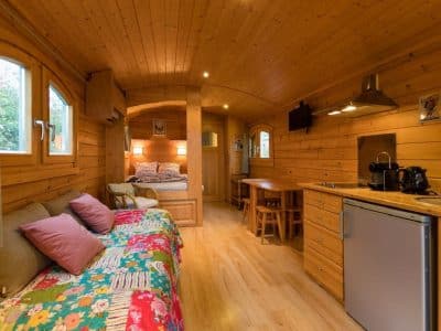 Gîte en bois chaleureux avec salon coloré et cuisine équipée, idéal pour un séjour unique.