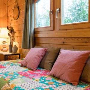 Chalet en bois chaleureux avec coussins colorés et lumière douce, Auvergne-Rhône-Alpes.