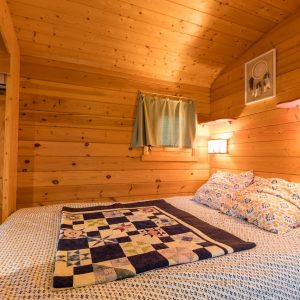 Chalet en bois chaleureux avec literie colorée et ambiance cocooning.