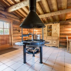 Cabane en bois en Auvergne-Rhône-Alpes avec une cheminée centrale et un intérieur chaleureux.