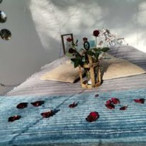 Hébergement insolite en Provence : chambre romantique décorée de roses et dun plaid bleu.