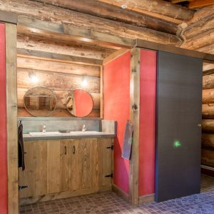 Salle de bain moderne dans un chalet en bois, avec lavabo et miroir.