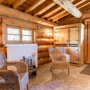 Cabane en bois dans les Alpes, avec chaises en osier et ambiance chaleureuse.