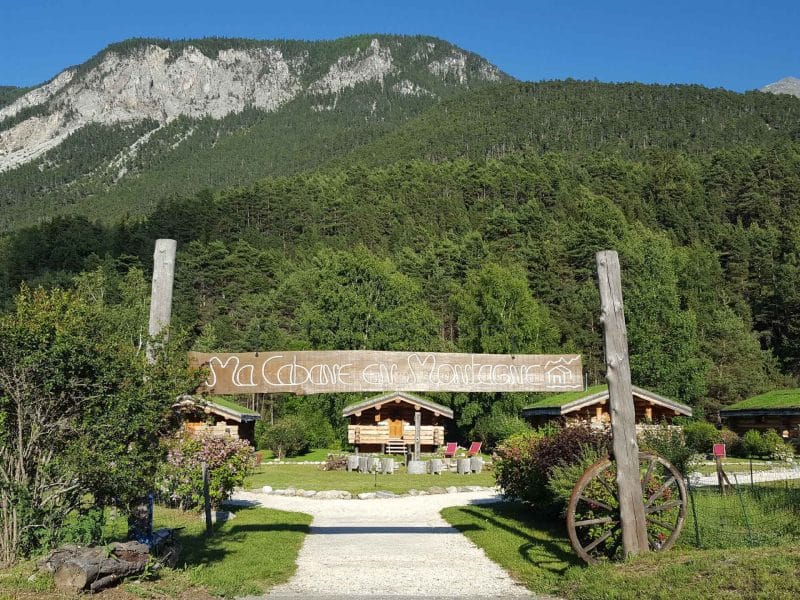 Chalets en bois entourés de montagnes verdoyantes et dune nature luxuriante.