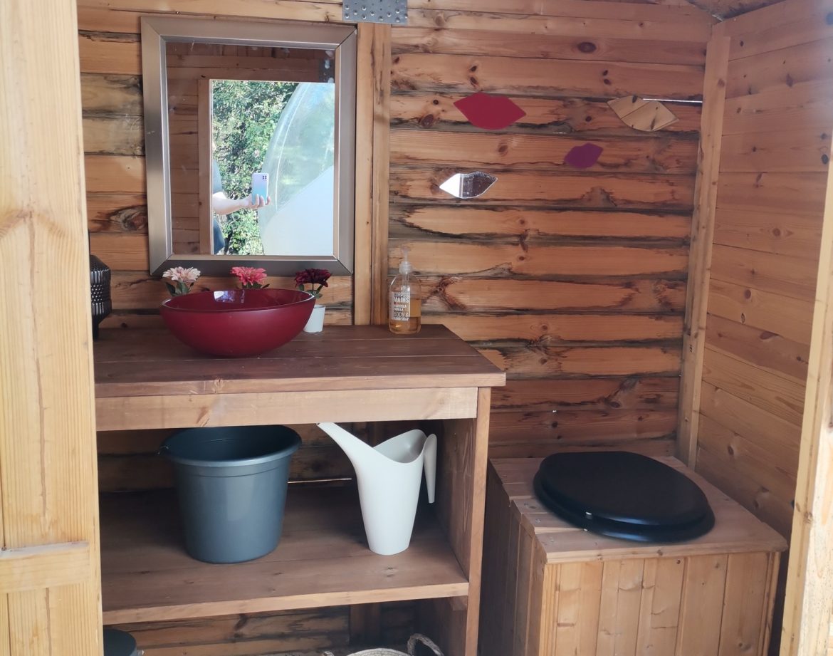 Cabane en bois avec lavabo et étagères, ambiance chaleureuse et naturelle.