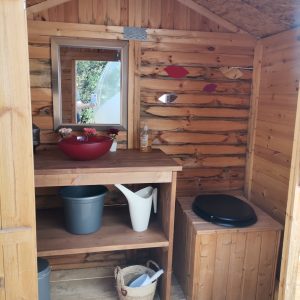 Cabane en bois avec lavabo et étagères, ambiance chaleureuse et naturelle.