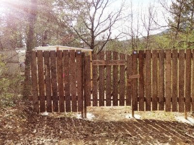 Cabane en bois dans la nature, entourée darbres et dun portail en bois rustique.