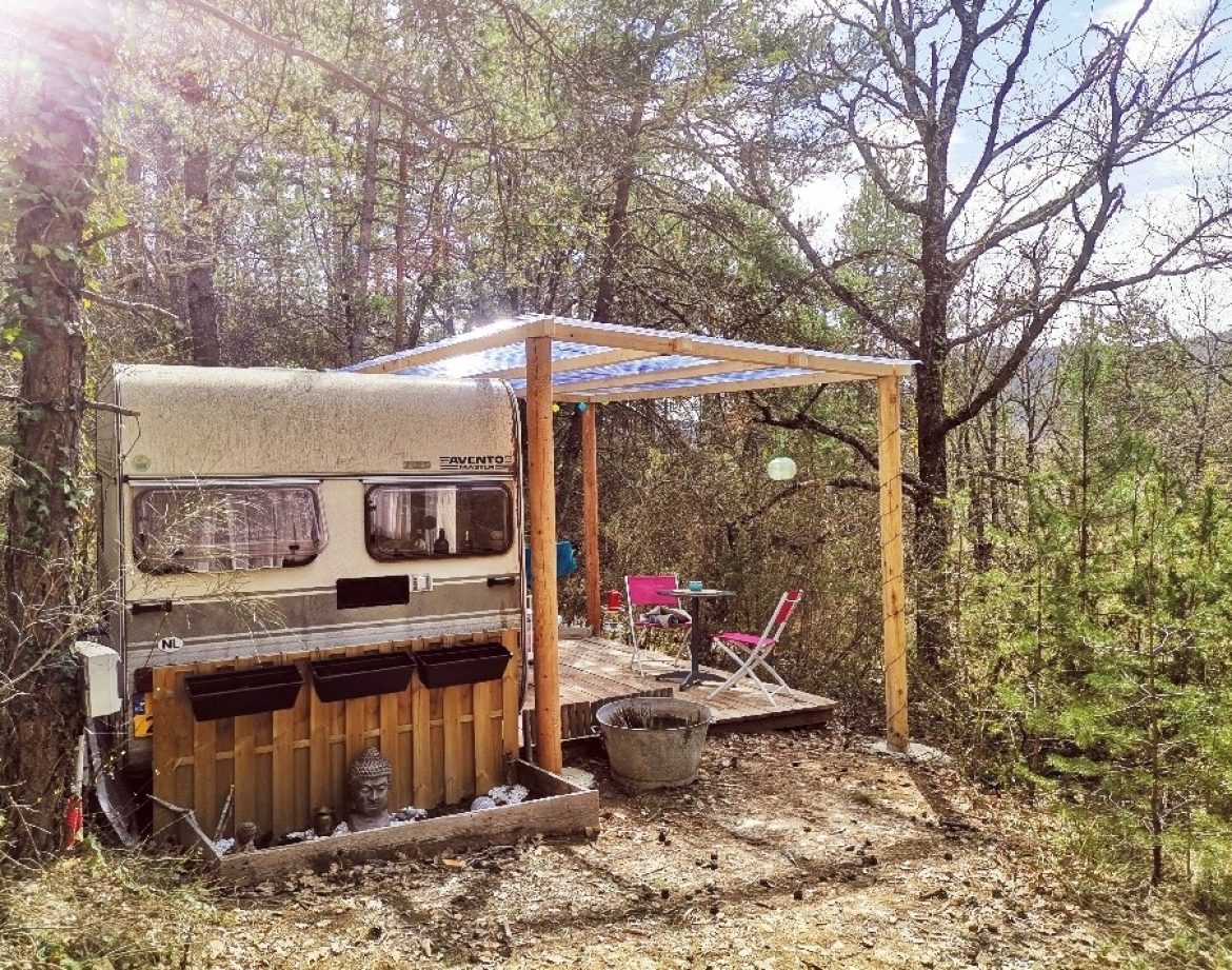 Caravane vintage sous un auvent, entourée de verdure en Provence-Alpes-Côte dAzur.