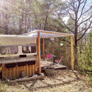 Caravane vintage sous un auvent, entourée de verdure en Provence-Alpes-Côte dAzur.