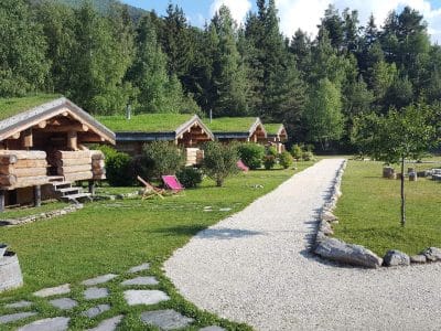 Cabanes en bois avec toits végétalisés, entourées de verdure en Auvergne-Rhône-Alpes.
