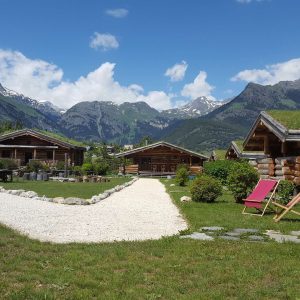 Cabins en bois avec toits végétalisés, entourées de montagnes majestueuses.