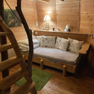 Cabane en bois cosy avec un lit douillet et un escalier en bois.
