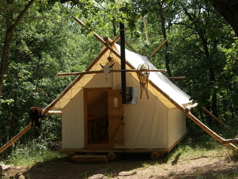 Tente en pleine nature, entourée darbres, offrant un séjour insolite et confortable.