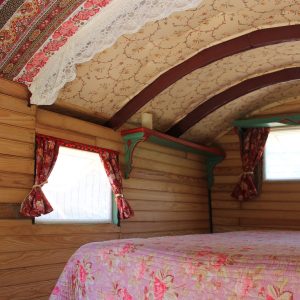 Hébergement insolite en roulotte, intérieur chaleureux avec des motifs floraux et des fenêtres