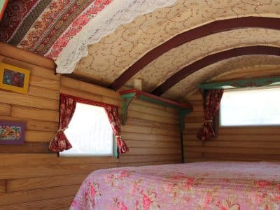 Hébergement insolite en roulotte, intérieur chaleureux avec des motifs floraux et des fenêtres