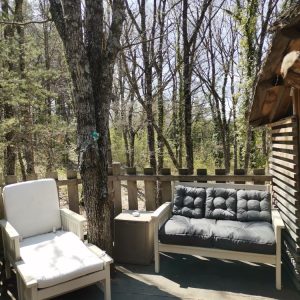 Cabane en bois avec salon extérieur, entourée darbres verdoyants en Provence.