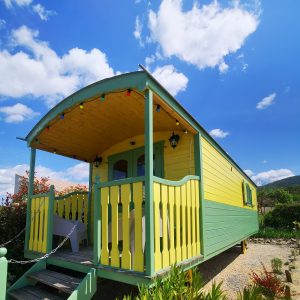 Roulotte colorée en Auvergne-Rhône-Alpes, avec terrasse et ciel bleu.