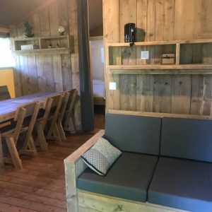 Hébergement insolite en bois avec un salon cosy et une grande table en bois.
