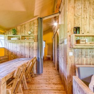 Hébergement insolite en bois avec une grande table conviviale et des murs chaleureux.