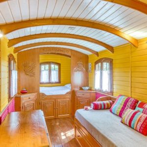 Roulotte colorée avec intérieur en bois, lit douillet et décor chaleureux.