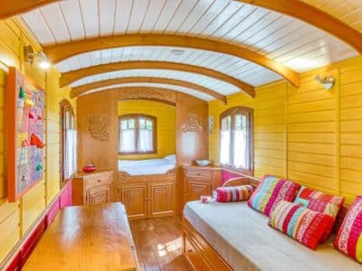 Roulotte colorée avec intérieur en bois, lit douillet et décor chaleureux.