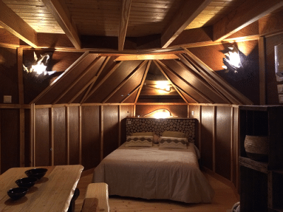 Hébergement insolite en cabane avec un lit confortable et des murs en bois chaleureux.