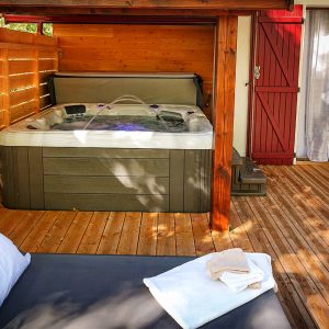 Hébergement insolite en Midi-Pyrénées avec jacuzzi sur une terrasse en bois.