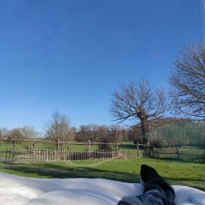 Hébergement insolite en bulle transparente, vue sur un ciel bleu et un paysage verdoyant.