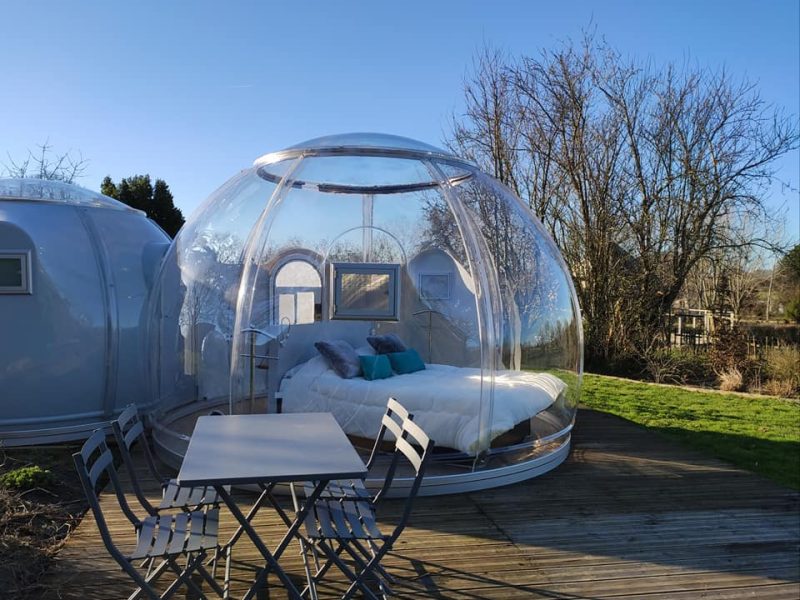 Dôme transparent en Nouvelle-Aquitaine avec lit douillet et terrasse en bois.