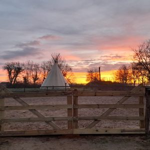 Teepee unique en Bourgogne, avec un coucher de soleil vibrant en toile de fond.