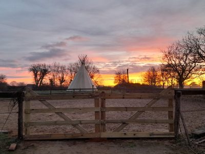 Teepee unique en Bourgogne, avec un coucher de soleil vibrant en toile de fond.